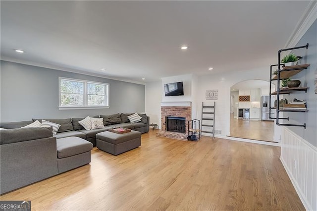 living room featuring crown molding, a fireplace, and light hardwood / wood-style flooring