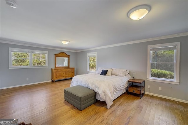 bedroom with multiple windows, ornamental molding, and light hardwood / wood-style flooring