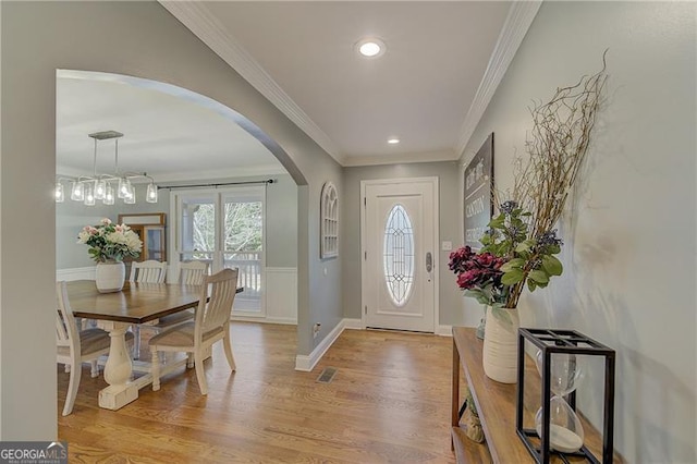 foyer with ornamental molding and light wood-type flooring