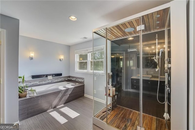 bathroom with hardwood / wood-style floors and a relaxing tiled tub