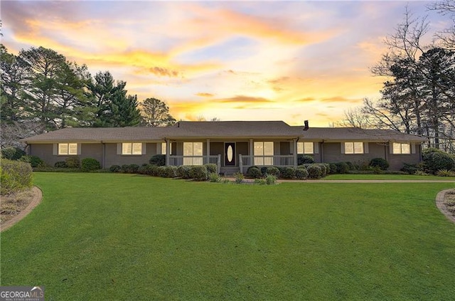 ranch-style home featuring covered porch and a lawn