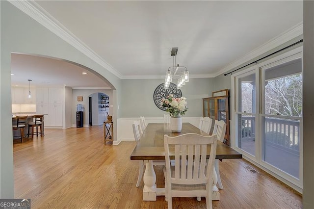 dining room with ornamental molding and light wood-type flooring