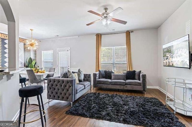 living room featuring dark hardwood / wood-style flooring and ceiling fan with notable chandelier