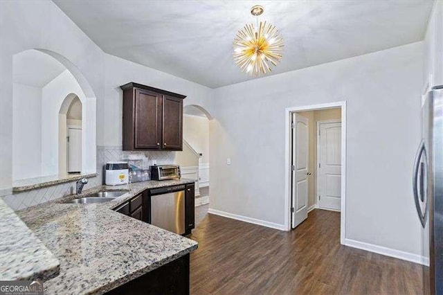 kitchen featuring dark wood-type flooring, sink, decorative light fixtures, appliances with stainless steel finishes, and light stone countertops