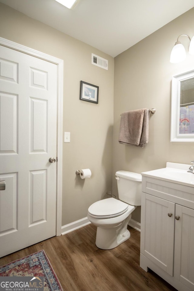 bathroom featuring wood-type flooring, vanity, and toilet