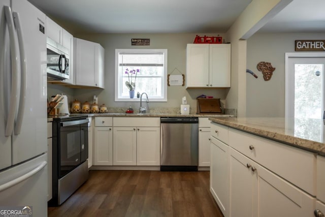 kitchen featuring a healthy amount of sunlight, light stone countertops, stainless steel appliances, and white cabinets