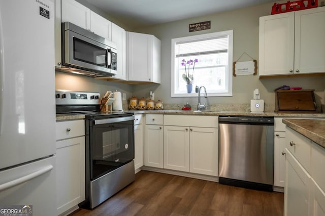 kitchen with dark wood-type flooring, sink, light stone counters, stainless steel appliances, and white cabinets