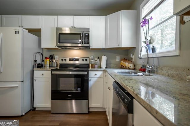 kitchen with white cabinetry, stainless steel appliances, light stone countertops, and sink