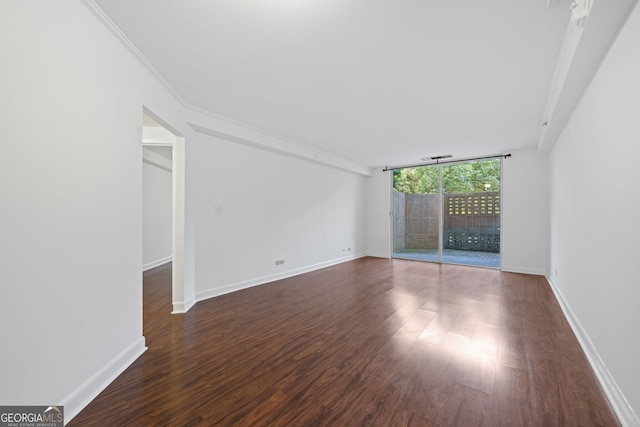 unfurnished room featuring crown molding, dark wood-type flooring, and a wall of windows