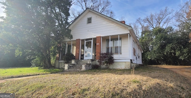 bungalow-style home featuring covered porch and a front yard