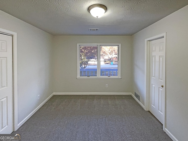 empty room featuring dark carpet and a textured ceiling