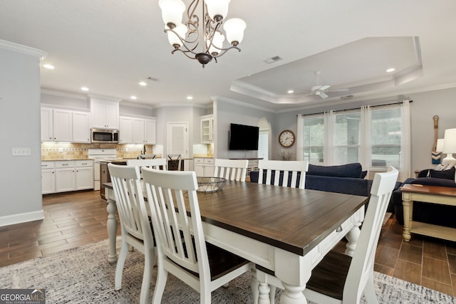 dining space with a tray ceiling, ornamental molding, and ceiling fan