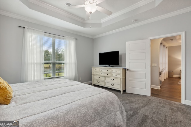 bedroom featuring a raised ceiling, dark colored carpet, ceiling fan, and crown molding