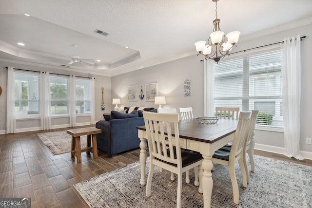 dining room featuring a raised ceiling, crown molding, dark wood-type flooring, and ceiling fan with notable chandelier