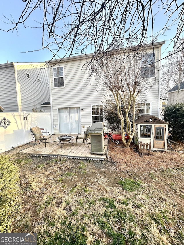 back of house featuring an outdoor structure, a patio area, and an outdoor fire pit