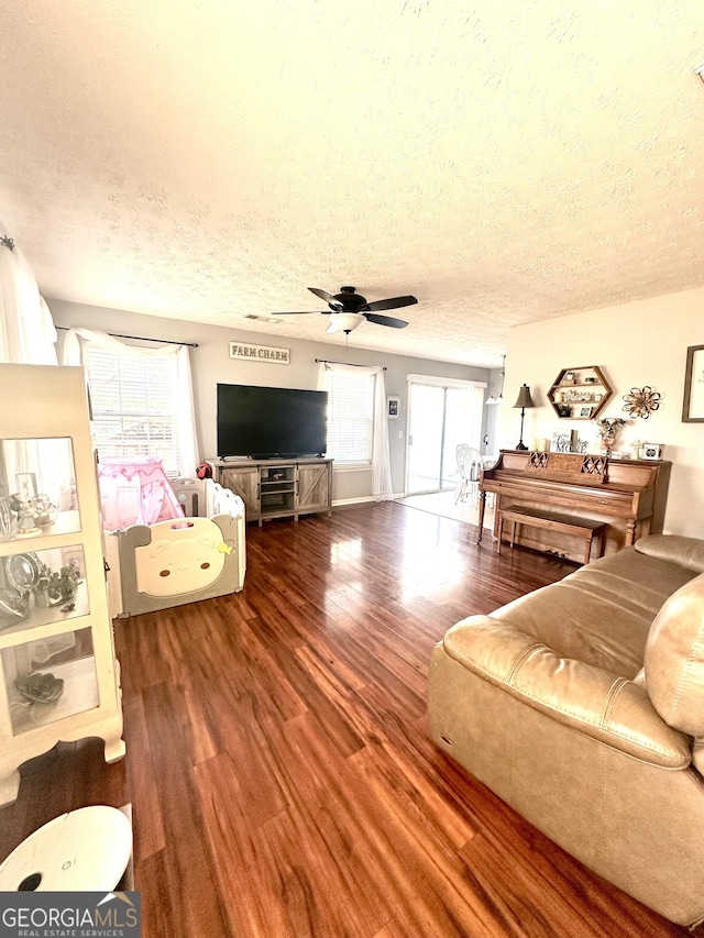 living room with wood-type flooring, ceiling fan, and a textured ceiling