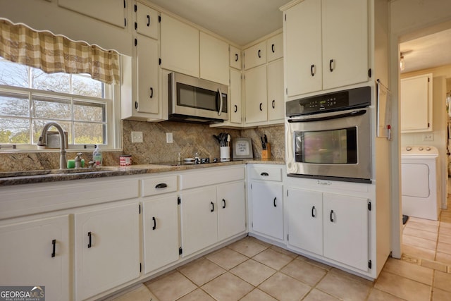 kitchen featuring sink, appliances with stainless steel finishes, white cabinetry, washer / clothes dryer, and decorative backsplash