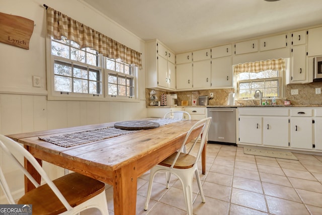 kitchen featuring white cabinets, stainless steel dishwasher, sink, and a wealth of natural light