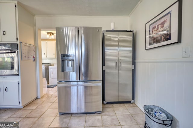 kitchen featuring light tile patterned flooring, white cabinetry, ornamental molding, appliances with stainless steel finishes, and washer and clothes dryer