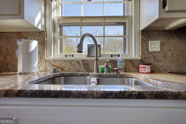 details featuring sink, dark stone counters, and decorative backsplash