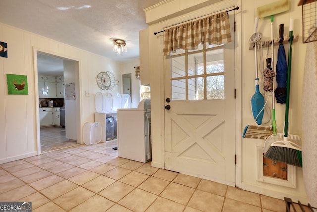 entryway featuring washer / dryer, light tile patterned floors, and a textured ceiling