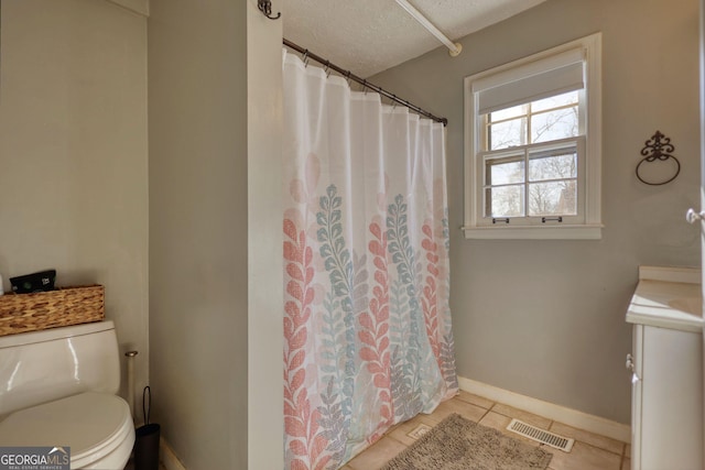 bathroom with tile patterned flooring, toilet, a textured ceiling, and walk in shower