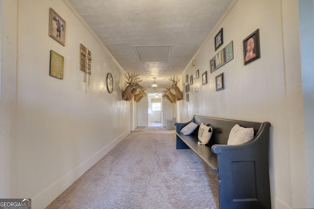 hallway featuring ornamental molding, light carpet, and a textured ceiling