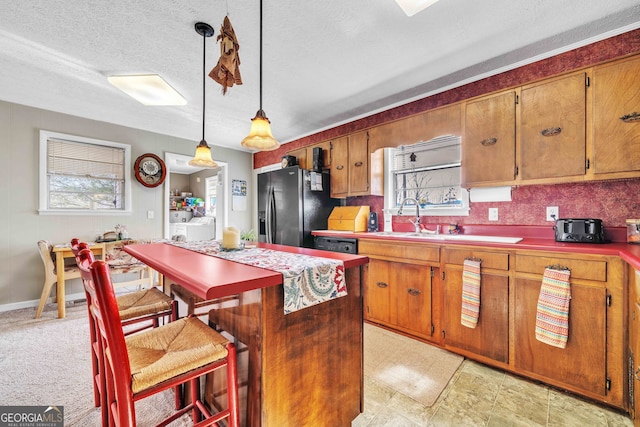 kitchen featuring stainless steel refrigerator with ice dispenser, a healthy amount of sunlight, a kitchen bar, and pendant lighting