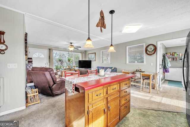 kitchen with wood walls, decorative light fixtures, light colored carpet, ceiling fan, and a textured ceiling