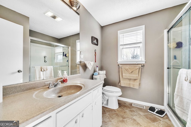 bathroom with vanity, a shower with door, toilet, and a textured ceiling