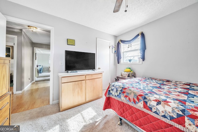 bedroom featuring ceiling fan, light colored carpet, and a textured ceiling