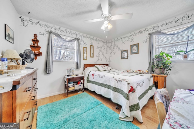 bedroom with ceiling fan, multiple windows, a textured ceiling, and light wood-type flooring