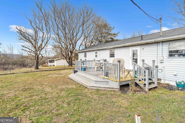 rear view of property featuring a wooden deck and a lawn