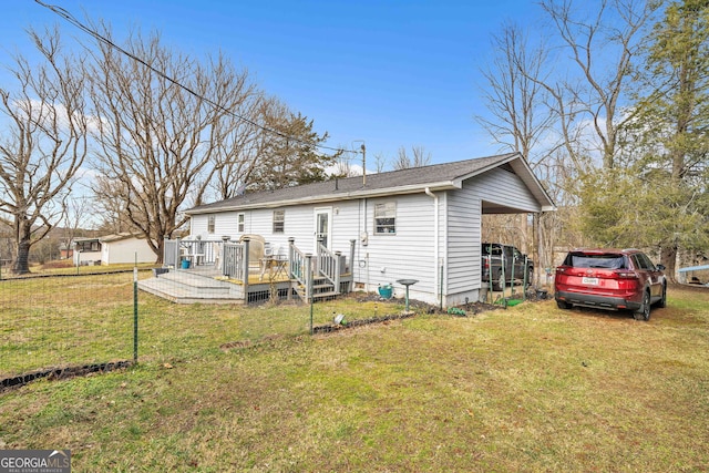 back of property featuring a wooden deck, a carport, and a lawn