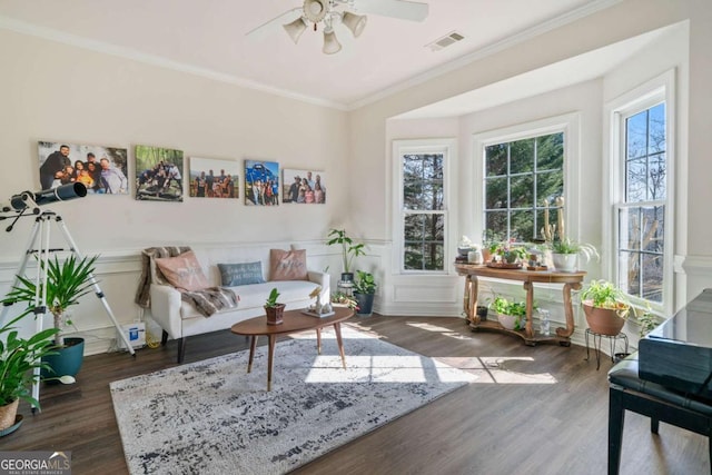 living area featuring crown molding, dark wood-type flooring, and ceiling fan