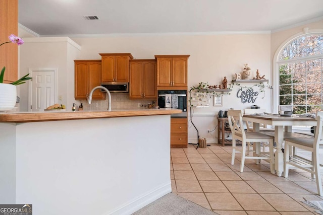 kitchen with sink, light tile patterned floors, ornamental molding, decorative backsplash, and oven