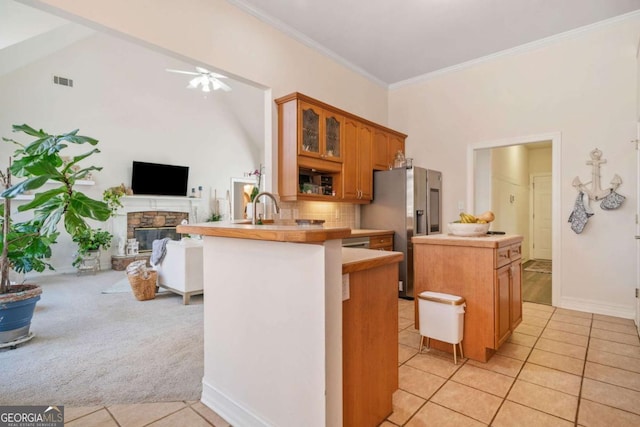 kitchen with stainless steel fridge with ice dispenser, kitchen peninsula, a kitchen island, ceiling fan, and a fireplace