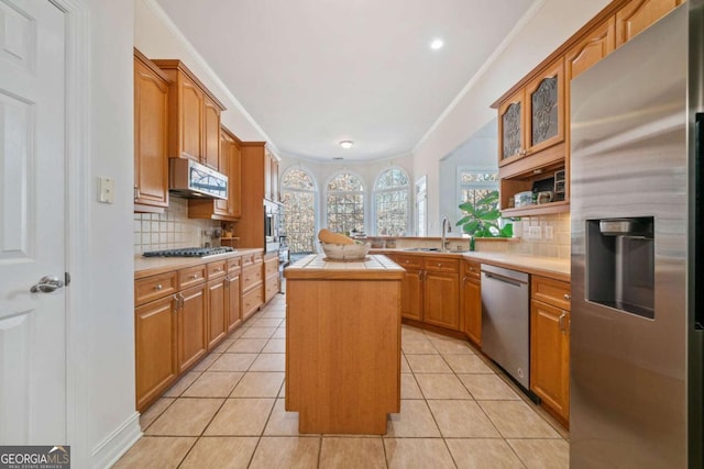 kitchen featuring light tile patterned flooring, stainless steel appliances, sink, and a kitchen island