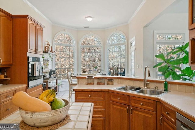 kitchen with ornamental molding, appliances with stainless steel finishes, sink, and light tile patterned floors