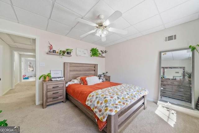 carpeted bedroom with ceiling fan and a drop ceiling