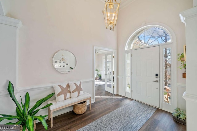 entrance foyer featuring an inviting chandelier, a towering ceiling, and dark wood-type flooring