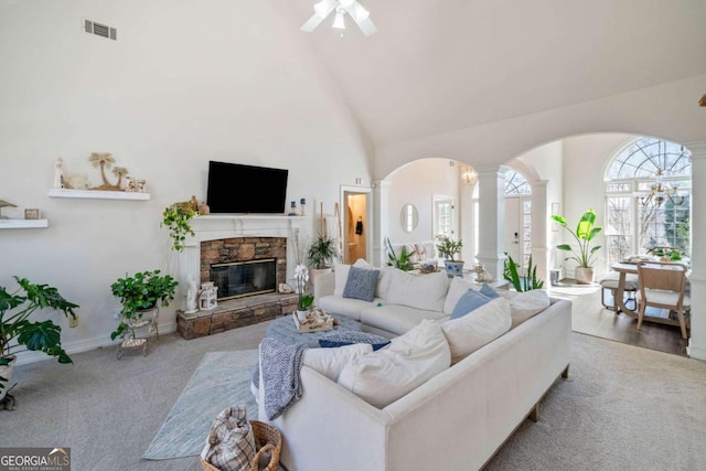 living room featuring ornate columns, a fireplace, high vaulted ceiling, ceiling fan, and light carpet