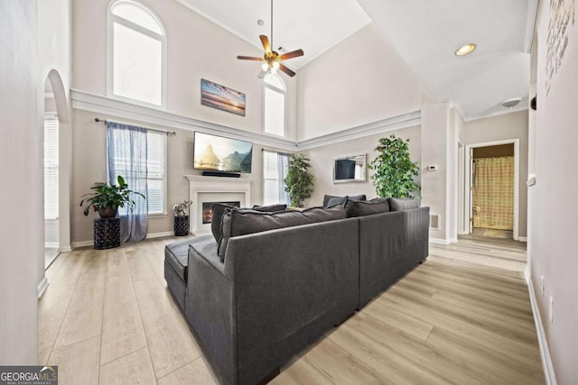 living room featuring a towering ceiling, light hardwood / wood-style floors, and ceiling fan