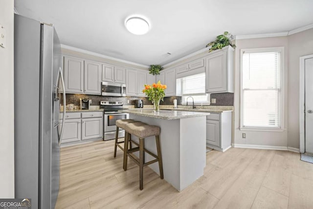 kitchen featuring stainless steel appliances, a kitchen breakfast bar, a center island, and gray cabinets