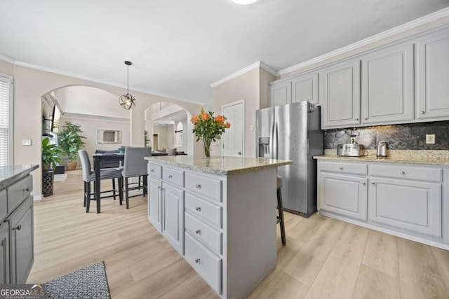 kitchen featuring stainless steel fridge, hanging light fixtures, and gray cabinetry