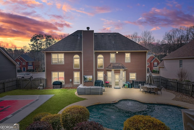 back house at dusk with a fenced in pool, a patio area, a lawn, and an outdoor hangout area