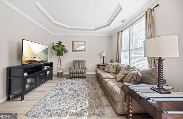 living room featuring ornamental molding, light hardwood / wood-style flooring, and a tray ceiling