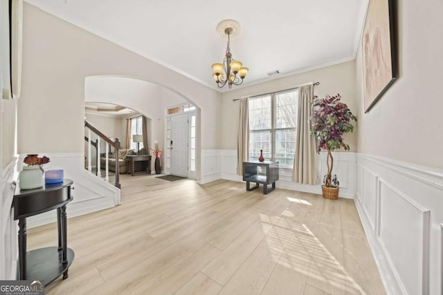 foyer entrance featuring ornamental molding, a chandelier, and light hardwood / wood-style floors