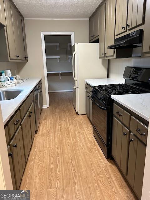 kitchen with sink, gas stove, a textured ceiling, and light wood-type flooring