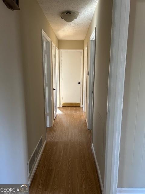 hallway with hardwood / wood-style floors and a textured ceiling